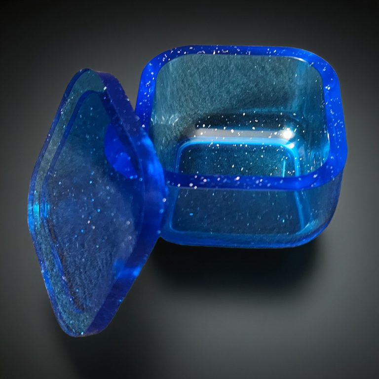 Blaues, viereckiges kleines Kästchen aus transparentem, glitzerndem Harz.