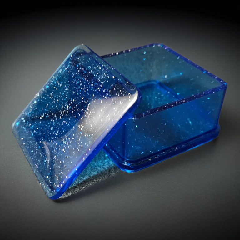 Blaue quadratische Dose mit Deckel aus glitzerndem, transparentem Harz.