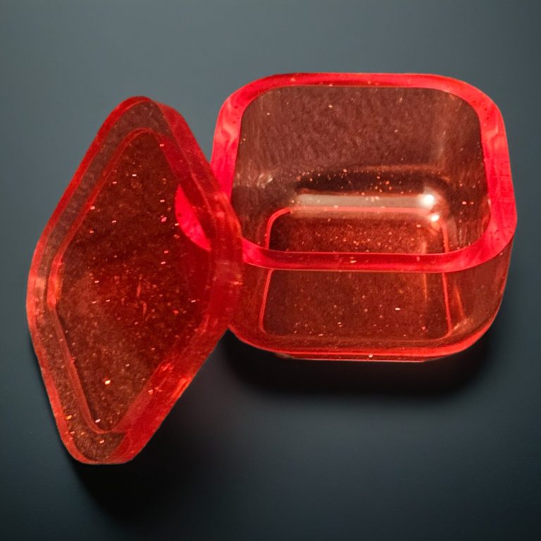 Rotes, viereckiges kleines Kästchen aus transparentem, glitzerndem Harz.
