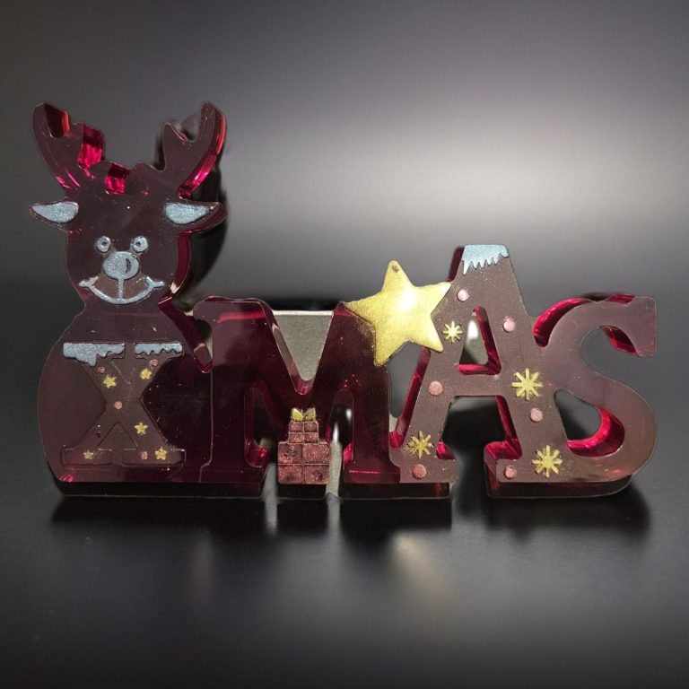 Rot-glänzender Weihnachtsdeko mit Rentier und dem Schriftzug "XMAS".