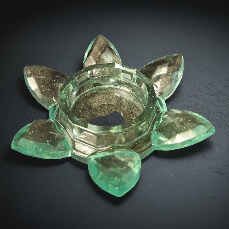 Grüner Teelichthalter aus Resin in Blumenform mit fächerartig angeordneten Blütenblättern – transparent mit Glitzereffekt.