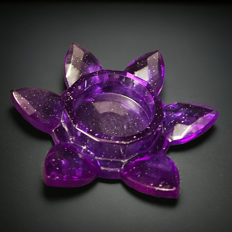 Lila Teelichthalter aus Resin in Blumenform mit fächerartig angeordneten Blütenblättern – transparent mit Glitzereffekt.