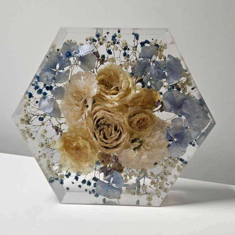 Hexagonale transparente Skulptur mit getrockneten Blumen in sanften Farben.