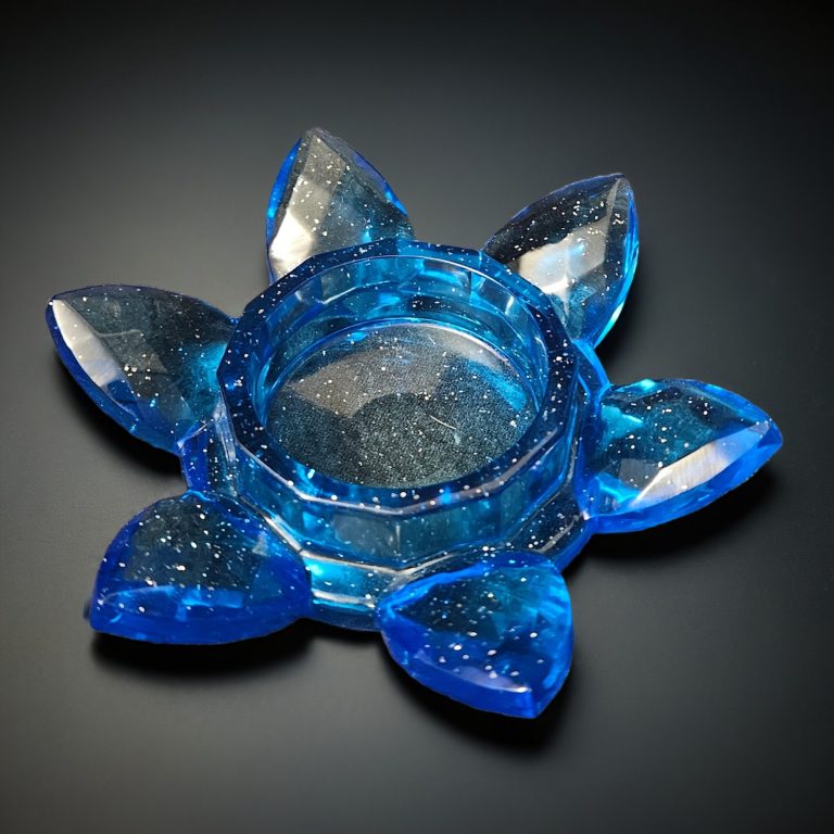 Blauer Teelichthalter aus Resin in Blumenform mit fächerartig angeordneten Blütenblättern – transparent mit Glitzereffekt.