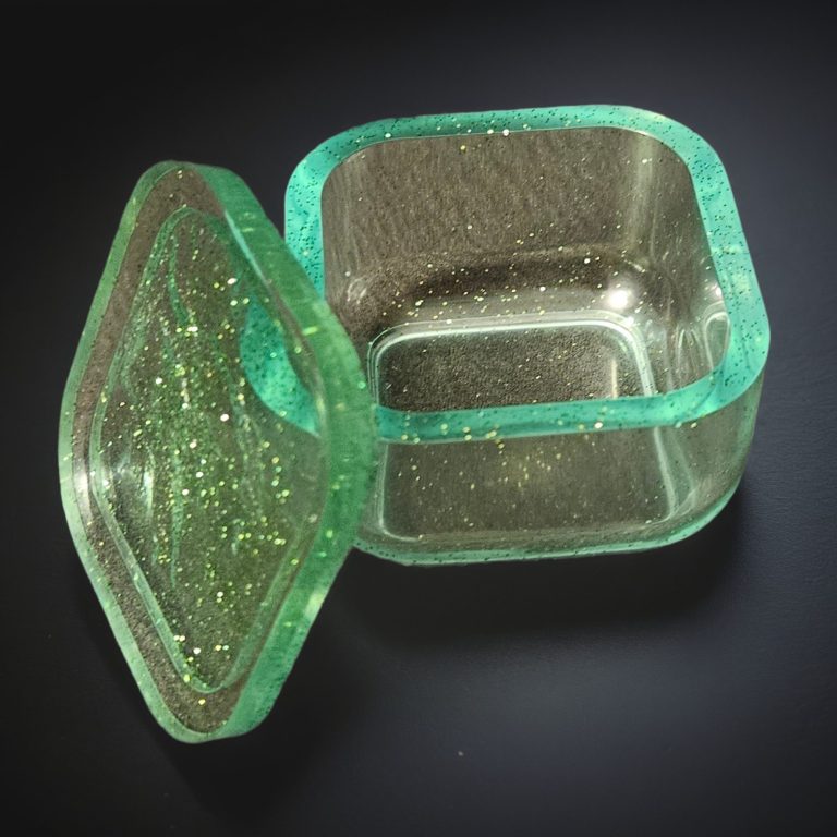 Grünes, viereckiges kleines Kästchen aus transparentem, glitzerndem Harz.