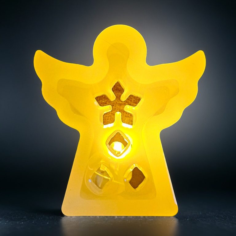 Gelbe Engel-Figur mit ausgeschnittenen Mustern, sanft beleuchtet.